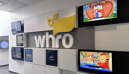 Photo of a wall with WHRO's logo and several TV screens